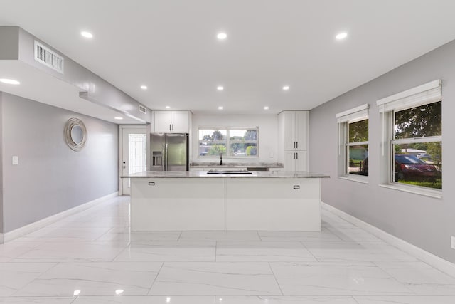 kitchen featuring white cabinetry, stainless steel refrigerator with ice dispenser, stone countertops, and a center island