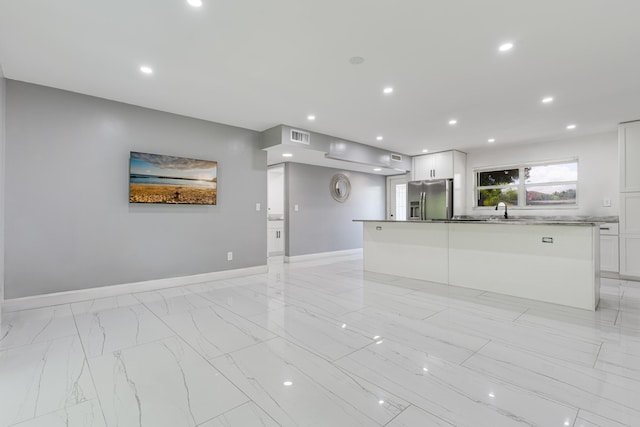 kitchen with white cabinetry, a center island, stainless steel fridge with ice dispenser, and sink