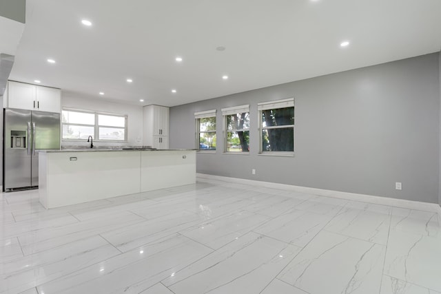 kitchen featuring white cabinets, stainless steel fridge, sink, and a kitchen island