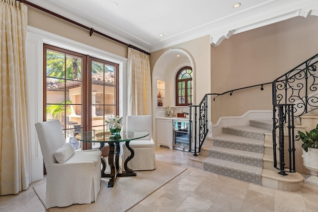 entryway featuring wine cooler, crown molding, and a healthy amount of sunlight