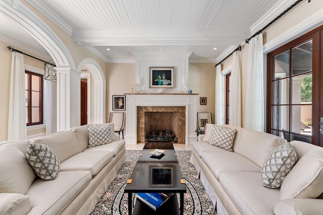 living room with ornamental molding, beam ceiling, and a premium fireplace