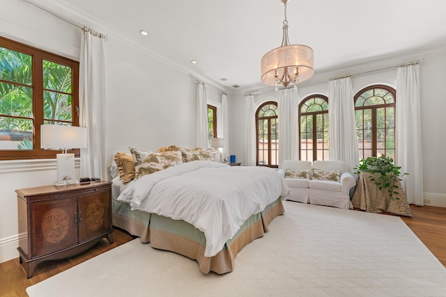 bedroom featuring an inviting chandelier, crown molding, hardwood / wood-style floors, and multiple windows