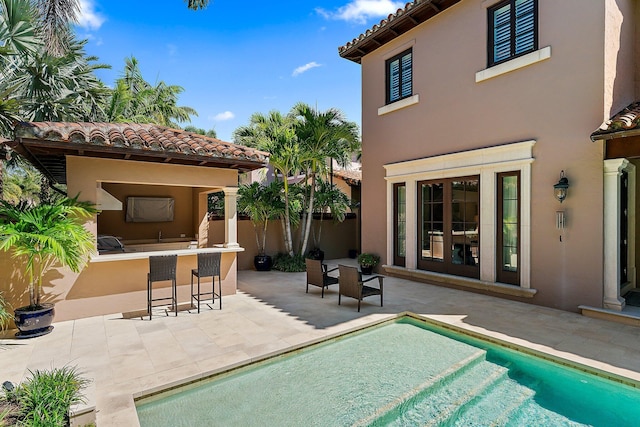 view of pool with exterior bar and a patio