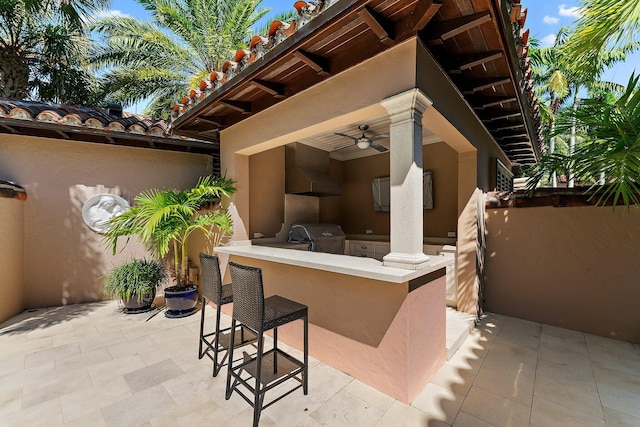 view of patio / terrace with area for grilling, ceiling fan, exterior bar, and exterior kitchen