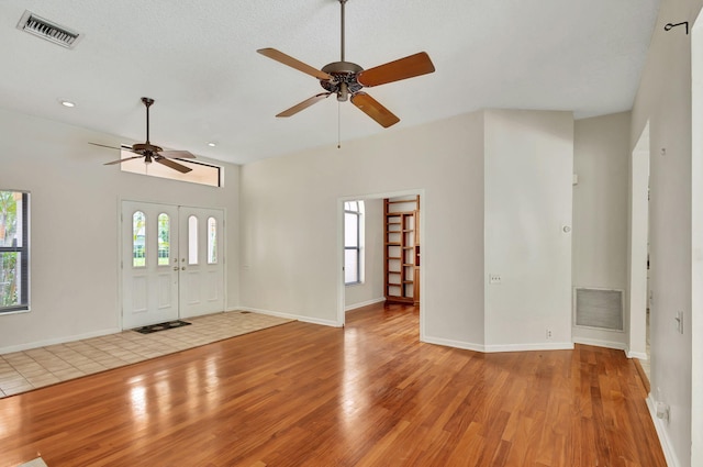 unfurnished living room featuring a textured ceiling, ceiling fan, and light hardwood / wood-style flooring