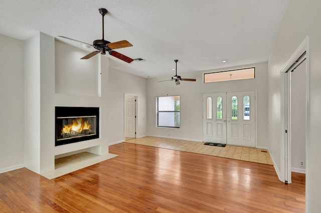 foyer entrance with ceiling fan, a textured ceiling, and light wood-type flooring