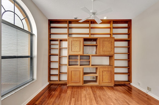 unfurnished living room featuring wood-type flooring, ceiling fan, and a textured ceiling