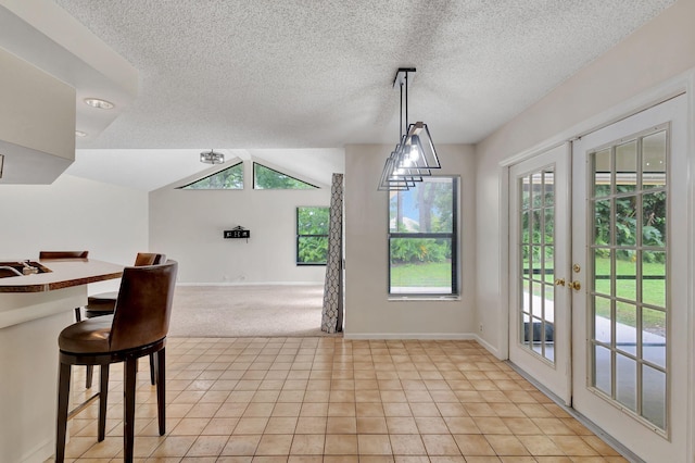 dining area featuring french doors, a textured ceiling, light tile patterned floors, and a healthy amount of sunlight