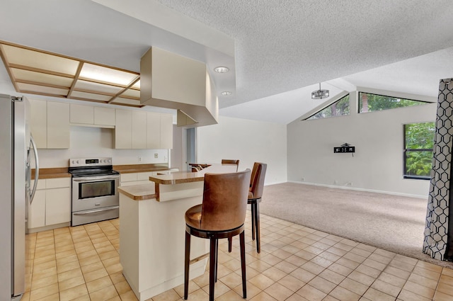 kitchen with appliances with stainless steel finishes, a kitchen breakfast bar, kitchen peninsula, lofted ceiling, and light colored carpet