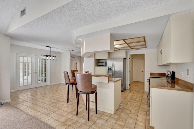 kitchen with white cabinets, light tile patterned floors, kitchen peninsula, appliances with stainless steel finishes, and a breakfast bar area