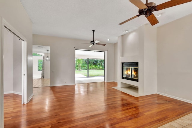 unfurnished living room featuring light hardwood / wood-style flooring, ceiling fan, and a textured ceiling