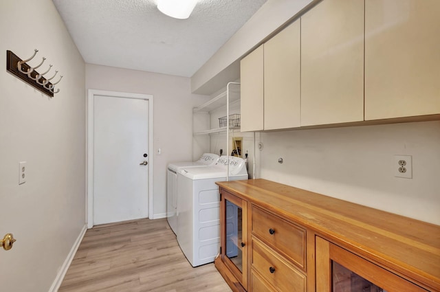 laundry area featuring cabinets, a textured ceiling, light hardwood / wood-style floors, and independent washer and dryer