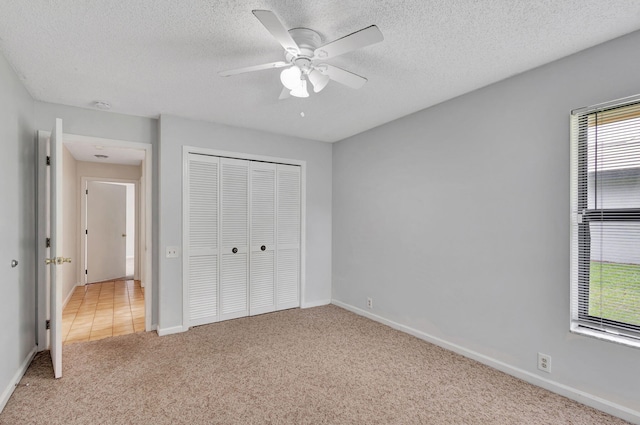 unfurnished bedroom with a closet, carpet, ceiling fan, and a textured ceiling