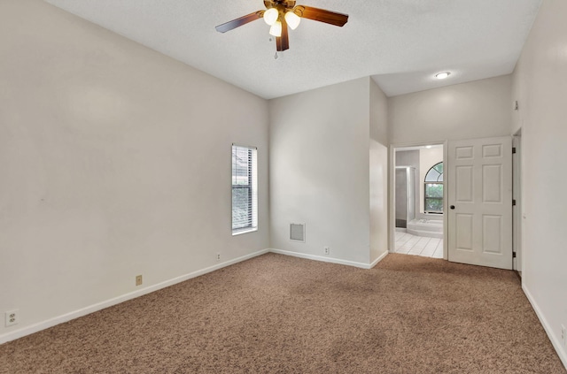 unfurnished room featuring ceiling fan, light colored carpet, and a textured ceiling