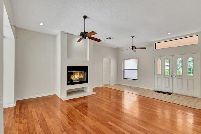 unfurnished living room with light wood-type flooring, a textured ceiling, and ceiling fan