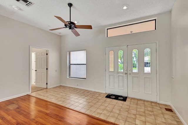 foyer featuring ceiling fan, a textured ceiling, light wood-type flooring, and french doors