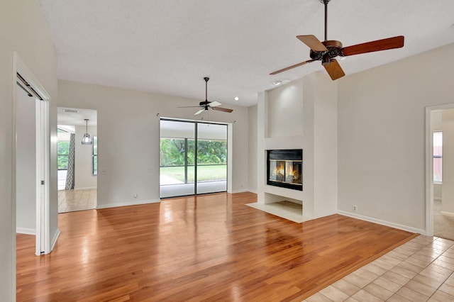 unfurnished living room with ceiling fan, light hardwood / wood-style floors, and a wealth of natural light