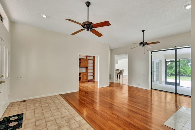 empty room featuring ceiling fan, a textured ceiling, and light hardwood / wood-style flooring