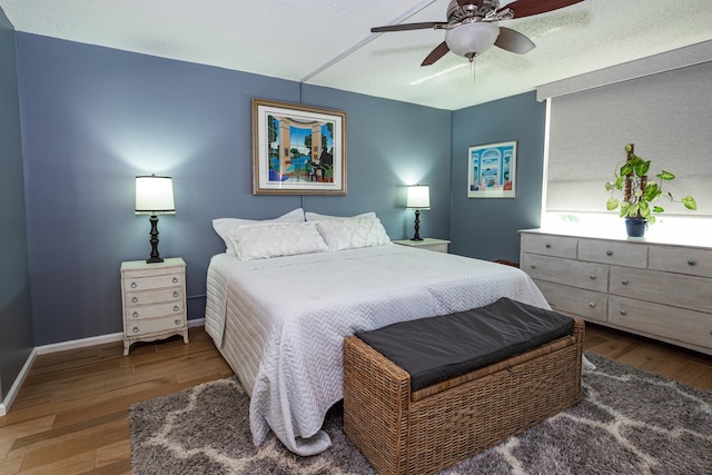 bedroom with wood-type flooring, ceiling fan, and a textured ceiling