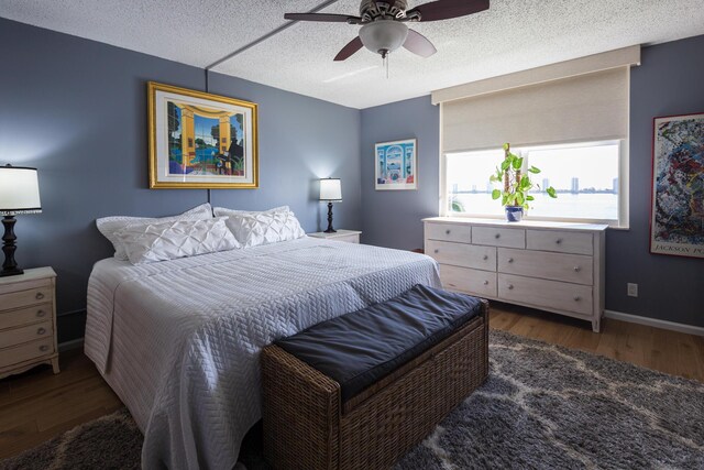 bedroom featuring ceiling fan, a textured ceiling, and dark wood-type flooring