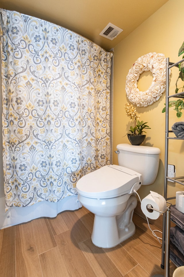 bathroom with wood-type flooring, toilet, and curtained shower