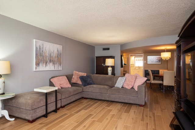 living room with a textured ceiling, a chandelier, and hardwood / wood-style flooring