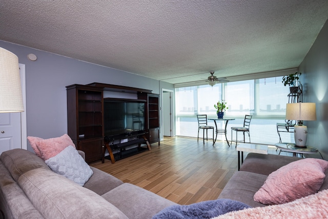 living room with light hardwood / wood-style flooring, ceiling fan, and a textured ceiling