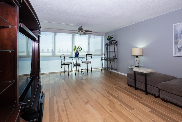 living room with a textured ceiling, ceiling fan, and hardwood / wood-style flooring