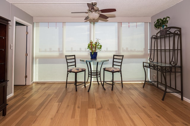 dining space with ceiling fan, a textured ceiling, and hardwood / wood-style floors