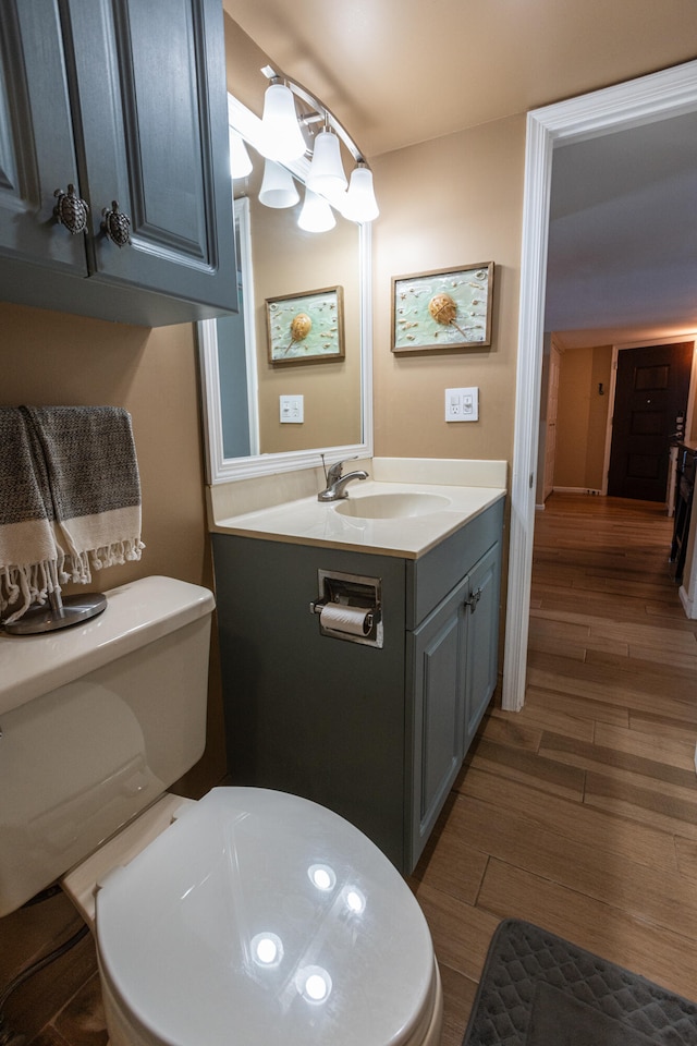 bathroom featuring wood-type flooring, vanity, and toilet