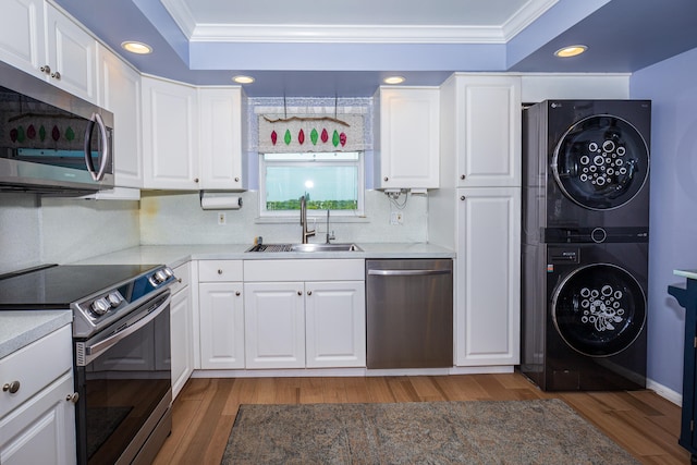 kitchen featuring white cabinets, appliances with stainless steel finishes, stacked washer / dryer, and sink