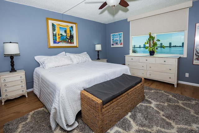 bedroom featuring ceiling fan, a textured ceiling, and dark wood-type flooring