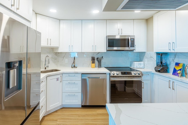 kitchen with appliances with stainless steel finishes, tasteful backsplash, white cabinetry, and sink