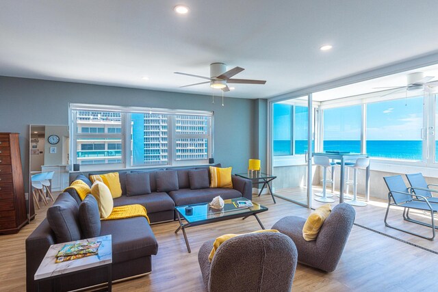 living room with ceiling fan, light hardwood / wood-style floors, and a water view