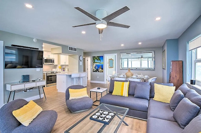 living room with ceiling fan and light hardwood / wood-style flooring