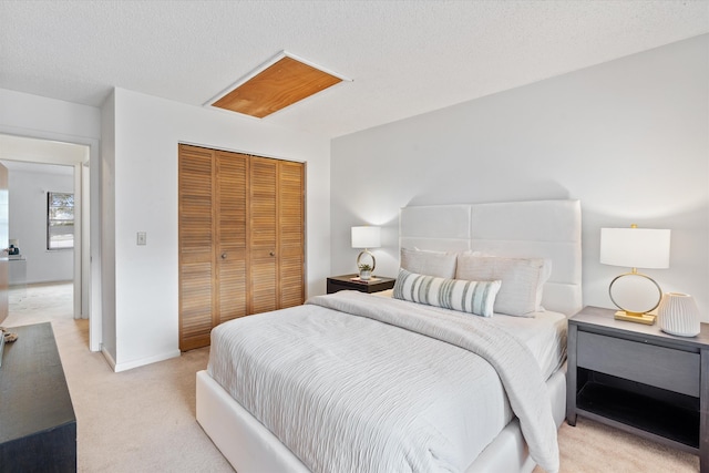 bedroom with a closet, light colored carpet, and a textured ceiling