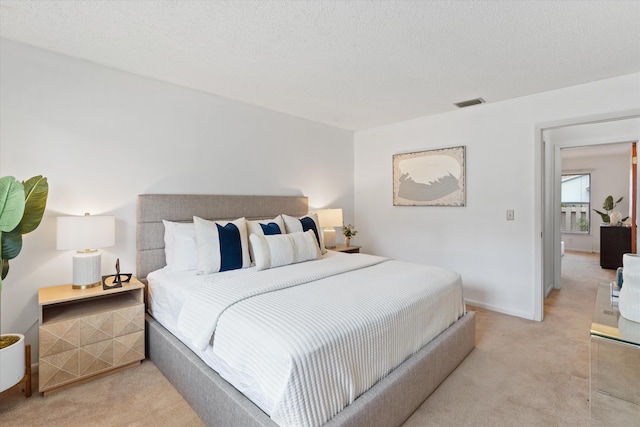 bedroom featuring light carpet and a textured ceiling