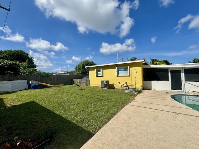 rear view of property featuring a yard, a fenced in pool, a patio area, and central air condition unit