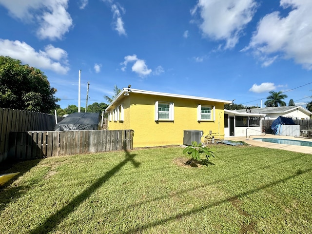 back of property with a fenced in pool, a sunroom, a yard, and cooling unit