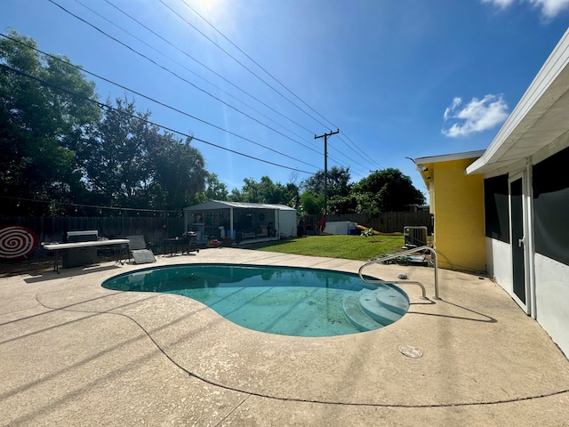 view of pool with a lawn, a patio area, and an outdoor structure