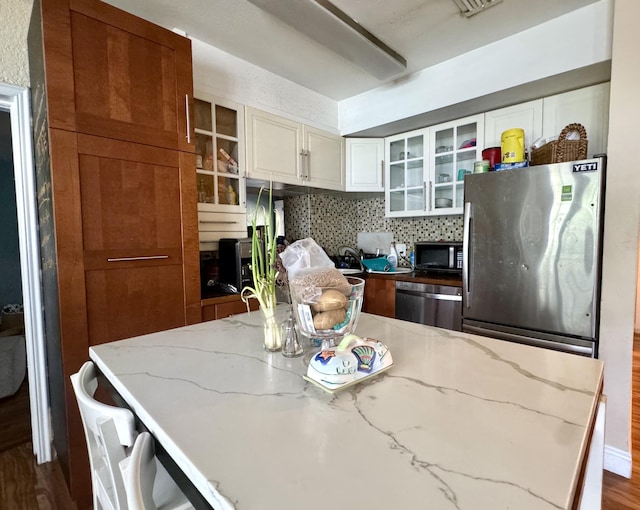 kitchen featuring stainless steel appliances, dark hardwood / wood-style floors, tasteful backsplash, light stone counters, and white cabinets