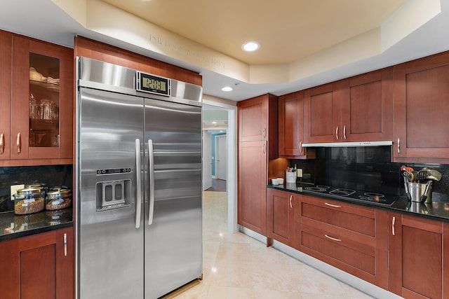 kitchen with black electric cooktop, glass insert cabinets, tasteful backsplash, and stainless steel built in refrigerator