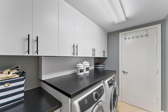 clothes washing area featuring cabinet space and washer and clothes dryer