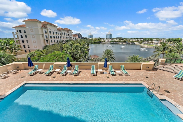 pool featuring a patio area, fence, and a water view