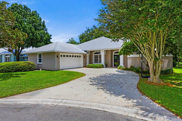 ranch-style house featuring a garage and a front lawn