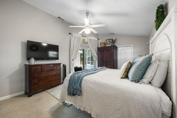 carpeted bedroom with a closet, vaulted ceiling, ceiling fan, and access to outside