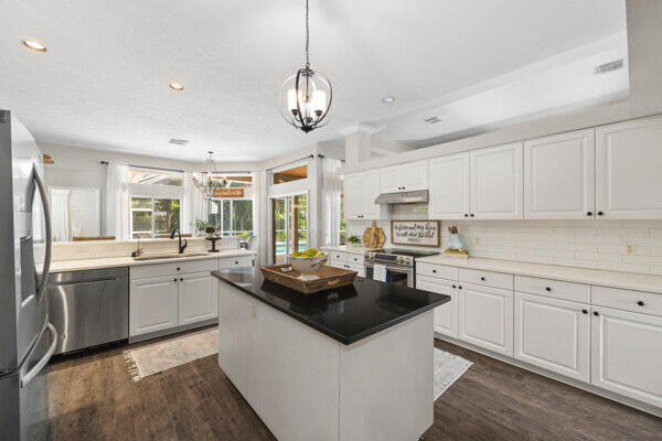 kitchen with white cabinets, stainless steel appliances, plenty of natural light, and a chandelier