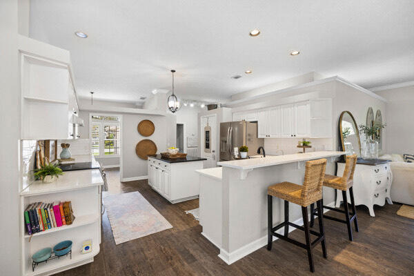 kitchen featuring stainless steel fridge, dark wood-type flooring, white cabinets, a center island, and decorative light fixtures