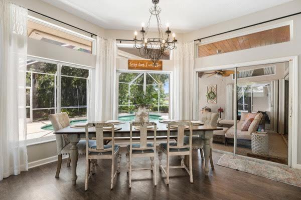 dining area with ceiling fan with notable chandelier, dark wood-type flooring, and a wealth of natural light