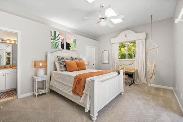 bedroom with light carpet, ceiling fan, ensuite bathroom, and sink